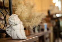 A Little Cherub Or Angel Stone Statue Is Placed On The Wooden Table. Interior Decoration Object And Background Photo.