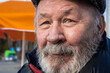 © GenоМ. - Old handsome smiling laughing man with blue eyes. Wise Senior aged Caucasian white man wearing a cap and warm jacket on spring day. Portrait of an elderly disabled pensioner close up.