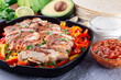Chicken Fajitas with bell pepper and onion in a pan, served with salsa Asada, sour cream, avocado and tortillas, horizontal