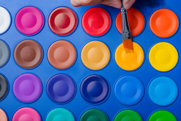 Brush for watercolor painting close-up and a set of watercolor paints. Colorful photography. Selective focus.