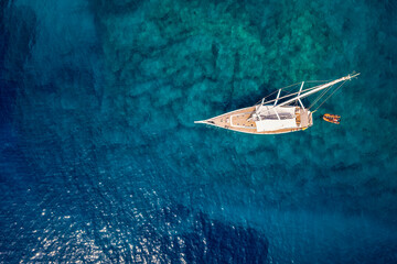 Wall Mural - aerial top down view to a sailing boat over the turquoise and emerald shining, mediterranean sea