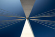 © Igor - Minimalist abstract architecture shot featuring a white concrete pillar of a suspension bridge with two bunches of suspension cables against a clear blue sky