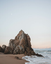 Vertical Shot Of An Idyllic Sandy Coast With Rocky Cliffs At Sunset