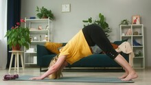 Blonde Pensioner Woman Standing In Downward Facing Dog Pose On Gym Mat, Elderly Sportswoman Trainer Doing Yoga On Floor In Living Room, Healthy Back. Exercising And Meditating In Morning, Long Life