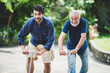 © chokniti - senior father and hipster adult son are happy love and relaxing together at nature outdoor park, mature family of elderly caucasian beard man playing fun with family in retirement leisure time