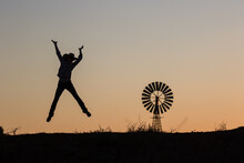 Happy Cowgirl Jumping And Windmill In Silhouette