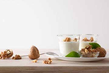 Wall Mural - Yogurt with nuts in glass bowl on plate isolated background