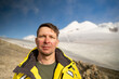 Portrait of a tired serious man in the mountains. Tourist climber on the background of Mount Kazbek.