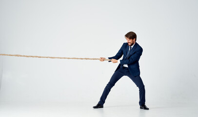 Poster - business man in a suit pulls the rope studio light background