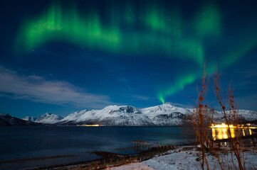 Northern lights on snow covered mountains in the polar region of Norway in the starry night