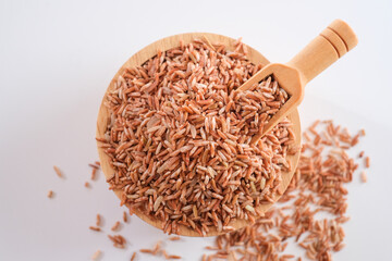 Wall Mural - Germinated Sangyod brown GI Muang Phatthalung rice in the wooden bowl and scoop on white background. Healthy food.This rice nose have lot of various kinds of nutrients.Top view. Flat lay. 