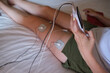 © jordi - electrostimulation treatment at home, electrodes on the leg of an unrecognizable woman, getting a treatment of tens, ems or massages to improve muscle health and improve blood circulation.