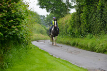 Pretty Young Woman And Her Coloured Horse Riding Along The Narrow Country Lanes Of Rural Shropshire Wearing Safety Gear To Be Seen By Other Road Users And Stay Safe.