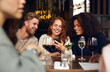 © Southworks - Cheerful friends looking at phone in wine bar