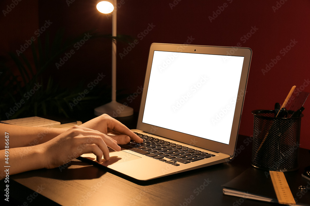 Woman working with laptop in office at night