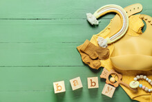 Composition With Baby Clothes, Bib And Toys On Color Wooden Background, Closeup