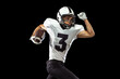 Close-up portrait of American football player playing in sports equipment, helmet and gloves isolated on dark studio background. Concept of sport, competition