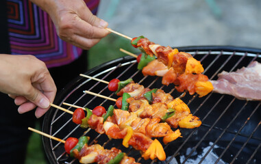 Wall Mural - Closeup of  fresh raw  chicken barbecue on gridiron with woman's hands. 