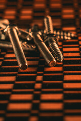 Canvas Print - Vertical closeup shot of silver screws and bolts on a patterned surface