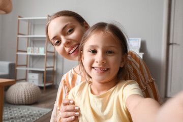 Poster - Young woman and her little daughter taking selfie at home