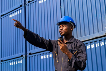  african amarican man working control loading freight containers at commercial shipping dock. cargo freight dock and import export logistic concept.