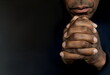© herlanzer - man praying to god with hands together Caribbean man praying on black background with people stock photos stock photo