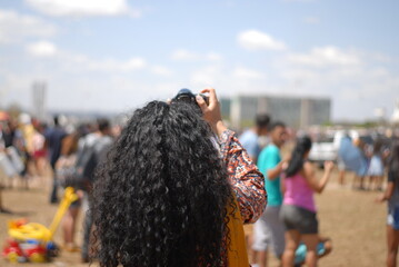 Curly Girl with a camera taking pictures in modern architecture Brasilia Brazil Desfile 7 de Setembro Parade September 7th