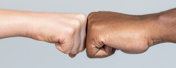 Wall Mural - Closeup of multicultural friends giving fist bump to each other. Black African American race male and woman hands giving a fist bump, multiracial diversity, immigration concept
