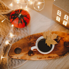 Wall Mural - cozy autumn still life with pumpkin and a cup of coffee on a knitted beige plaid with bokeh lights