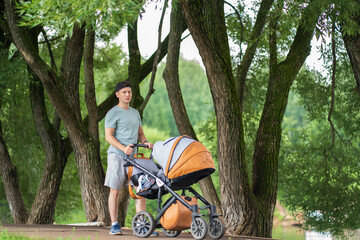 Young man with a stroller walking in the park in summer