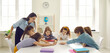© Studio Romantic - Female teacher and pupils group playing funny educational game at table desk in classroom. Smiling professional tutor and cheerful students. Education process at private elementary school