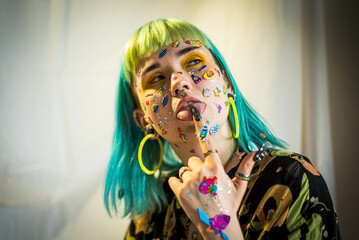 Wall Mural - Closeup fashion portrait young pretty beautiful girl with green and blue hair. Beautiful fashion girl with luxury professional makeup and funny emoji stickers glued on the face. Young woman