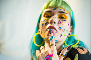 Wall Mural - Closeup fashion portrait young pretty beautiful girl with green and blue hair. Beautiful fashion girl with luxury professional makeup and funny emoji stickers glued on the face. Young woman