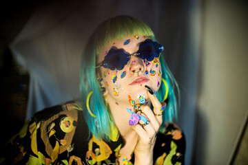 Wall Mural - Closeup fashion portrait young pretty beautiful girl with green and blue hair. Beautiful fashion girl with luxury professional makeup and funny emoji stickers glued on the face. Young woman sunglasses