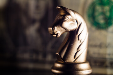 Poster - Closeup shot of a knight on a chessboard with a dollar bill on a background