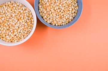 Canvas Print - Top view of corn grains on bowls isolated on an orange background