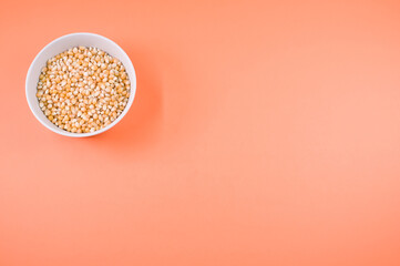 Wall Mural - Top view of corn grains on a bowl isolated on an orange background