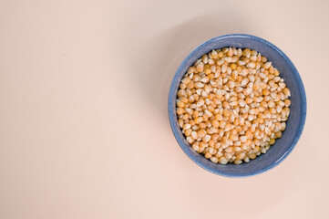 Canvas Print - Top view of corn grains on a bowl isolated on a light brown background