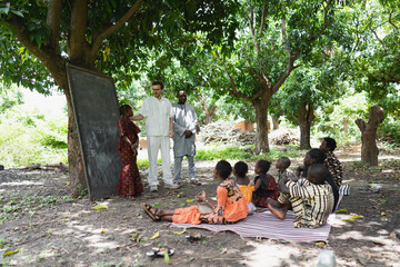 tall white volunteer teaching a group of children in an open air summer camp in a remote village in 