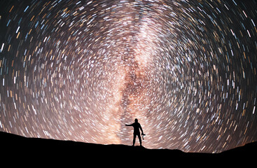 Wall Mural - starry night, silhouette stands on the hill and looking at the colorful star trails on the sky. nigh