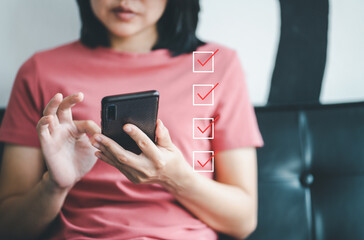 woman holding smartphone and marking on checklist box with marker red. customer service feedback on 