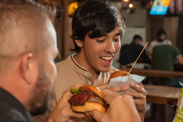 young man eating a tasty hamburger with bacon