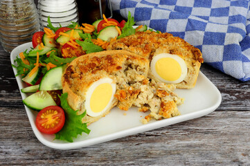 Wall Mural - Scotch egg quiche with shortcrust pastry and whole egg encased in pork sausage meat with fresh salad