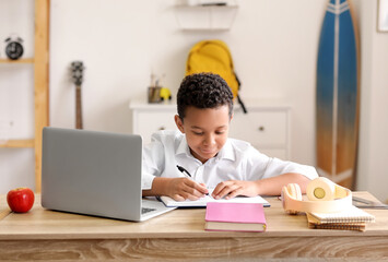 Wall Mural - Little African-American schoolboy studying online at home