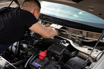 a man repairs a car. a man in blue special clothes to repair the car. engine parts machine repair maintenance breakage problem hands people man master