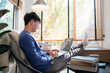 © snowing12 - young attractive asian man relaxing comfortably working on laptop in bright living room at his home.
