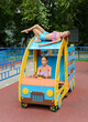 Tween caucasian girls sits on toy wooden car on playground