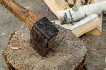 Wall Mural - an axe stuck in a wooden deck near chopped birch firewood.