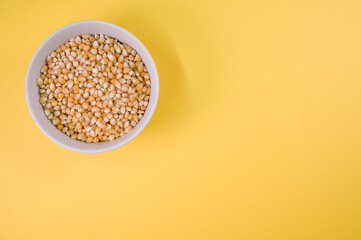 Sticker - Top view of corn grains on a bowl isolated on yellow background