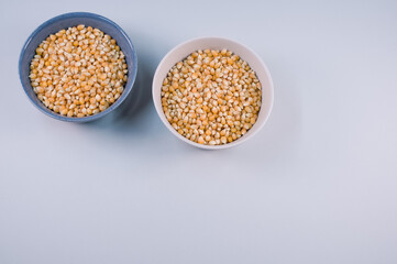 Sticker - Top view of corn grains on bowls isolated on light gray background